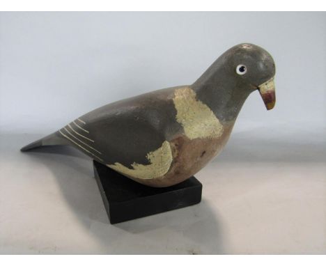 Folk art primitive painted decoy pigeon upon an associated black wooden plinth, 35cm long 