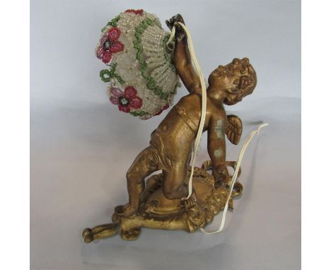Cast gilt metal figural lamp in the form of a cherub holding a beaded shade decorated with flowers, 20cm high 