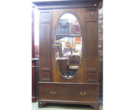 An inlaid Edwardian walnut wardrobe with satinwood crossbanding and moulded cornice over a central three quarter length oval 