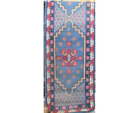 A Chinese full pile runner with red and colourful medallions upon a light blue ground, 320 x 80 cm 
