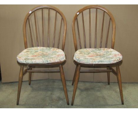 A pair of Ercol stained elm and beechwood hoop and stick back dining  chairs raised on simple turned, tapered and splayed sup