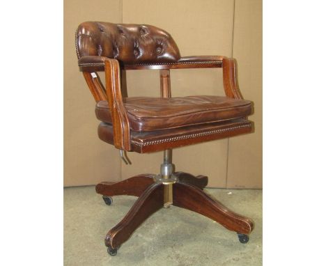 A reproduction swivel office desk chair with soft  tan leather upholstered pad seat, button back and arms, moulded frame and 