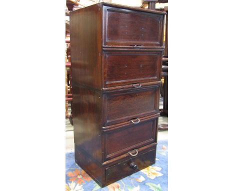 A vintage oak veneered floorstanding filing cabinet enclosed by four up and over rectangular panelled doors revealing tray sl