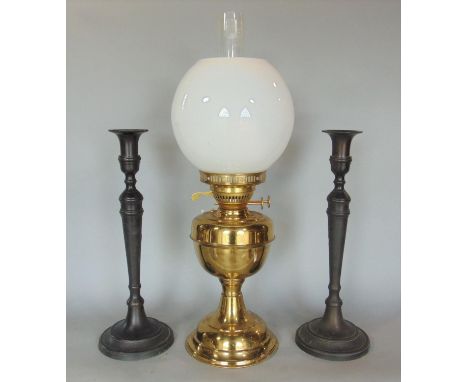 Brass duplex oil lamp with glass shade and flue, 54 cm high in total, together with a pair of iron candlesticks, 36 cm high (
