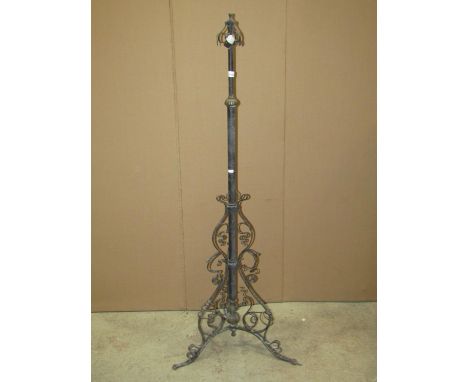 An Art Nouveau/craft style ironwork telescopic oil lamp standard with tubular stem, flanked by whip lash detail, swept tripod