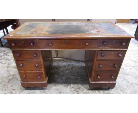 A Victorian mahogany kneehole twin pedestal, three sectional desk with worn inset leather panel top over an arrangement of ni