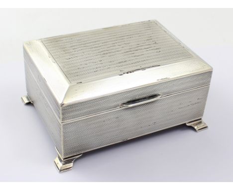 A George V hallmarked silver cigarette box with all-over engine-turned decoration, raised on ogee bracket feet, width 14cm, D