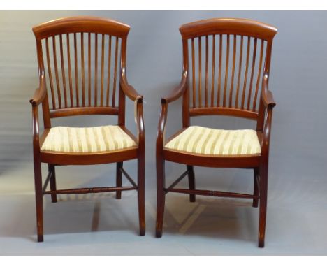 A pair of Victorian mahogany stick back arm chairs raised on sabre legs jointed b y stretchers