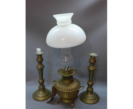 A pair of brass candlesticks together with a Victorian brass oil lamp having opaque glass shade, and a copper cooking pot