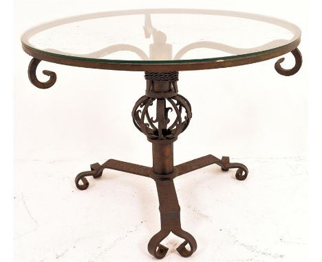 A wrought iron coffee table, standing on a decorative wrought iron tripod base, rising to a central pierced globe or orb desi