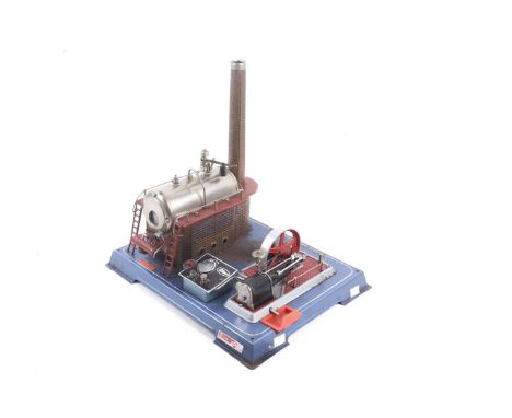 A Wilesco GS livesteam engine. Mounted on a tin base with engine and wheel complete with burner pan. 