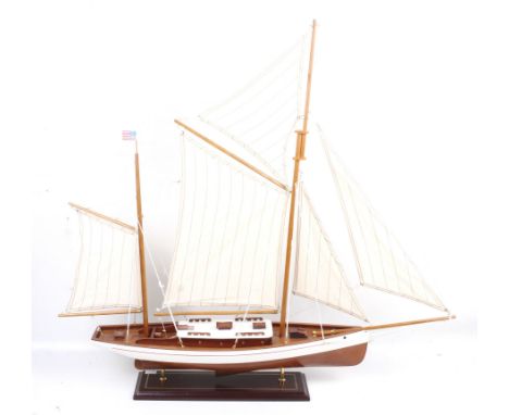 A wooden model of an American Schooner on stand. White body with red trim and cotton sails, on a wooden stand, H82cm x L90cm.