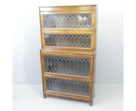 An early 20th century oak four shelf sectional stacking bookcase in the manner of Globe-Wernicke, with leadlight glazed lifti