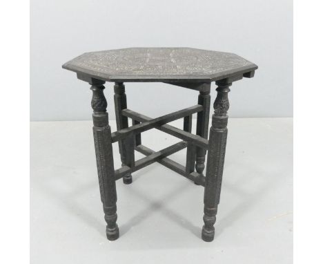 An Eastern ebonised octagonal-topped occasional table on folding base, with carved decoration. 38x41cm. 