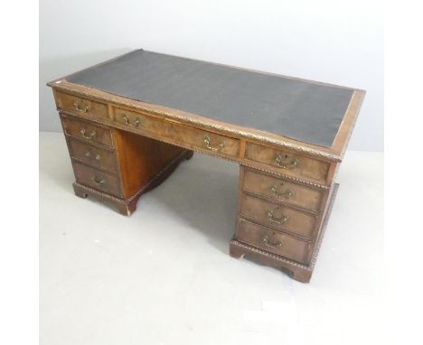 A Victorian style mahogany twin-pedestal writing desk, with faux leather skiver, nine drawers, carved decoration and bracket 