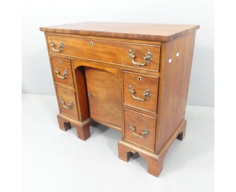 An antique oak and mahogany kneehole writing desk, with five drawers, cupboard under and raised on bracket feet. Overall 81x7