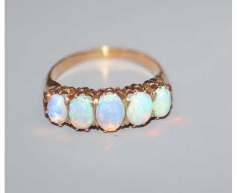 A yellow metal and graduated five stone white opal half hoop ring, size N.