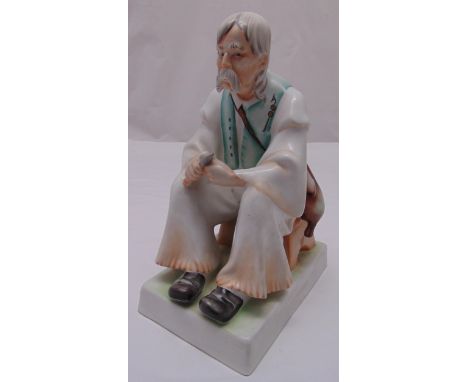 A Zsolnay Hungarian ceramic figurine of a seated peasant on raised rectangular plinth, 33cm (h)