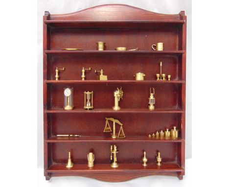 A quantity of brass miniatures to include a ships wheel, a clock, a balance scale and a wall mounted wooden display stand