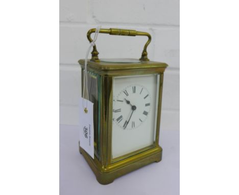 A brass cased carriage clock, the white enamel dial with Roman numerals, size including carry handle 17cm