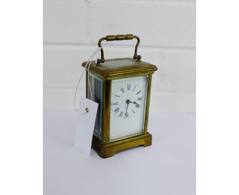 A small brass carriage clock with Roman numerals and carry handle to top, size including handle 15cm high