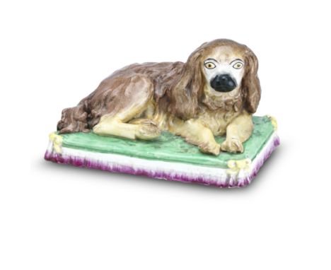 A large Staffordshire model of a reclining spaniel19th centuryModelled on a fine tasselled cushion, the corners hung with yel