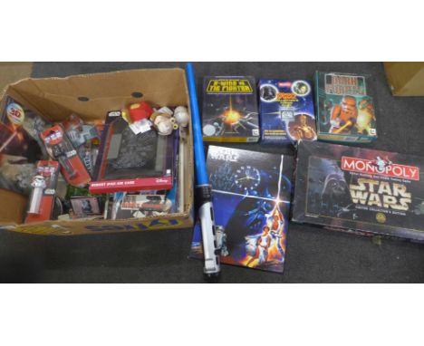 A collection of Star Wars memorabilia including a clock, a framed poster, two games, Monopoly, a light sabre, a TV remote, to