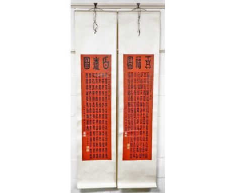 A cased set of two Chinese scroll pictures, each with a red rectangular panel depicting various symbols, in a material red bo