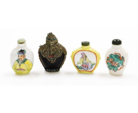 A group of four Chinese snuff bottles, to include three ceramic examples, two with figures one with dragons, on a yellow grou