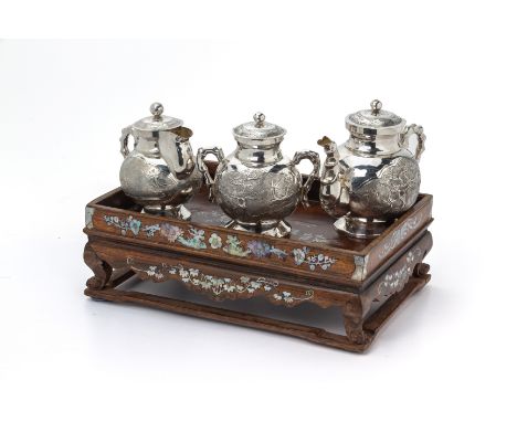 A PART TEA SERVICE ON MOTHER OF PEARL HARDWOOD STAND
Comprising a sugar bowl, teapot and milk jug decorated with foliage, the