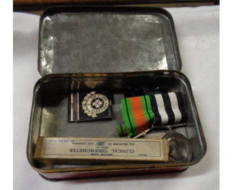 An old Thornes Toffee tin containing two 1950's St Johns Ambulance medals, a WWII defence medal, St Johns Ambulance match boo