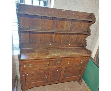 A 1.3m early 20th Century stained oak two part dresser with two shelf open plate rack over a base with two frieze drawers and