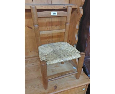 A vintage stained wood framed child's standard chair with woven rush seat panel and simple turned supports