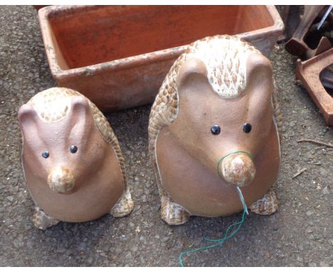 Two large ceramic garden statues depicting comical hedgehogs