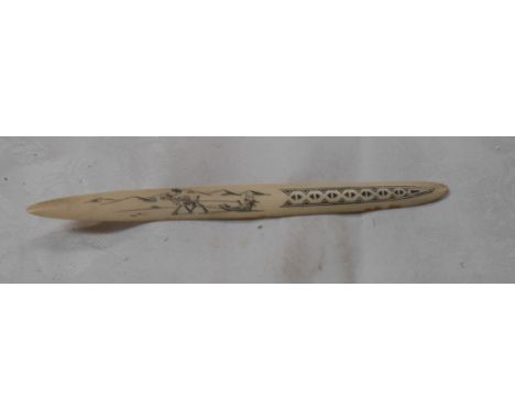 A carved bone letter opener with Inuit style scrimshaw decoration depicting a caribou pulling a sled