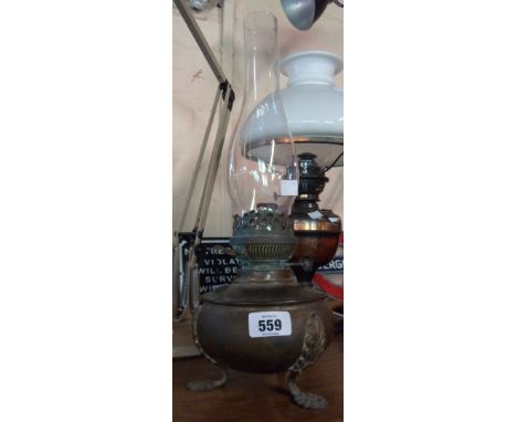 A brass oil lamp of globular form with three feet and glass chimney
