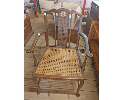 A vintage stained beech framed elbow chair with rattan back and seat panels, set on slender front cabriole supports