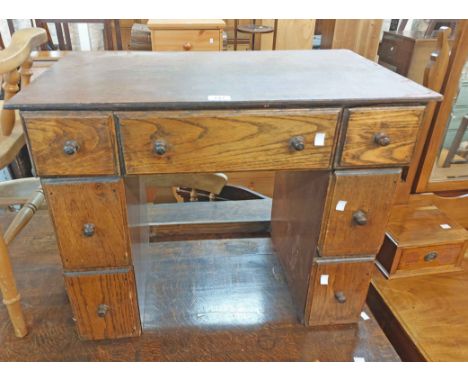 A 74cm vintage oak child's kneehole desk with three frieze drawers and four flanking pedestal drawers - wear