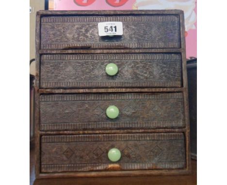 A vintage four drawer filing chest with textured faux wood covering and green early plastic handles
