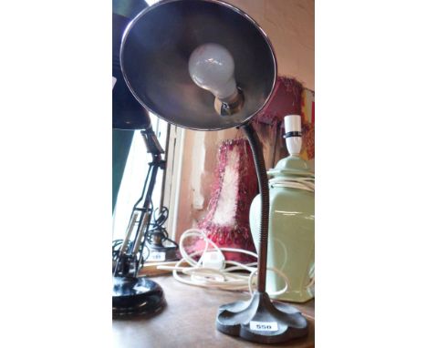 An old desk lamp with cast iron shell form base, articulated brass stem and chrome plated shade