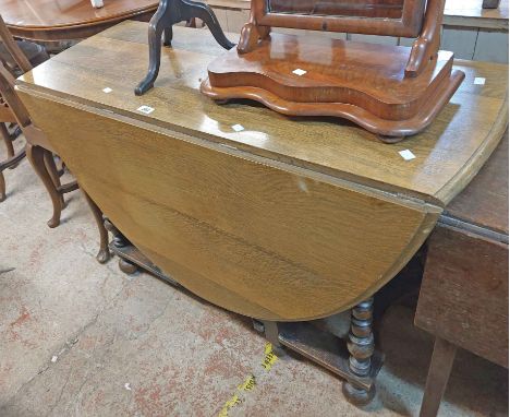 A 1.1m old oak gateleg dining table, set on bobbin turned supports