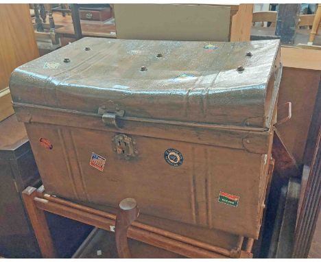 An old painted tin travelling trunk with transit label and dented top
