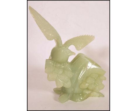 A Qing Dynasty (1644-1911) A Chinese white / light green Jade carved brush pot in the form of a magpie bird on naturalistic p