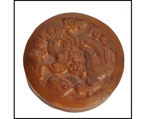 A Chinese Jade roundel seal of mottled brown colour carved with scrolling dragon motif and geometric patterns to the verso. M