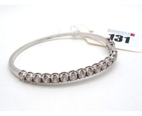 A Modern Diamond Set Bangle, claw set to the front with 14 brilliant cut stones, hinged to snap clasp, stamped "750" (interna