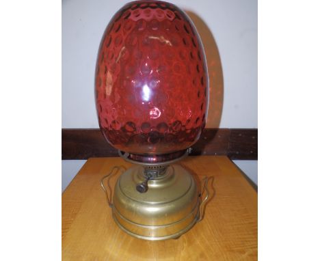 A 19thC oil lamp with large cranberry glass shade.
