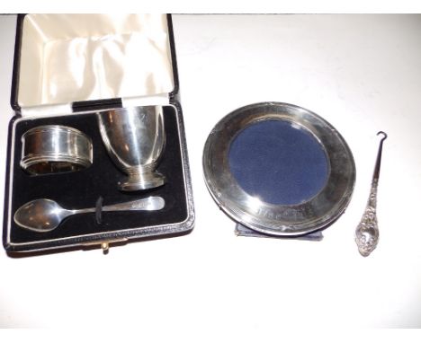 A cased three piece silver egg cup christening set, a circular photo frame, a button hook and an oyster fork, (6)