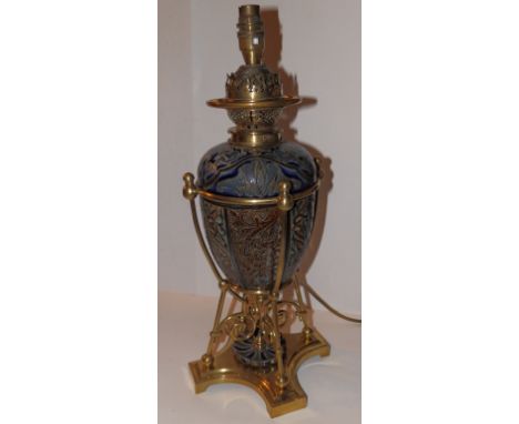 A Doulton Lambeth stoneware oil lamp with incised decoration of arabesque panels in muted shades of brown and blue, the ovoid