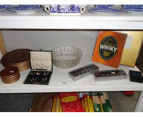 A shelf of miscellaneous including place mats, glass bowl etc.,