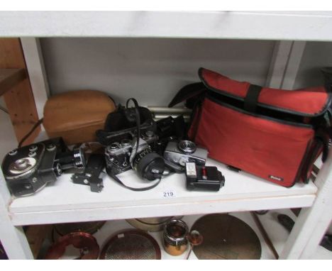 A shelf of camera's, video camera, tripod etc.,